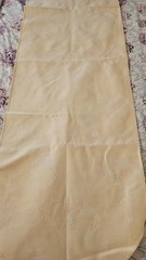Cream colored table runner with tassled ends and wreath pattern 66 x 13 1/2 in